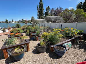 View of patio with a water view, fence, and a vegetable garden