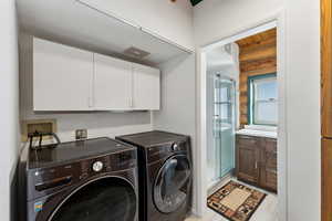 Washroom with cabinet space, visible vents, separate washer and dryer, and log walls