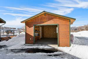 Snow covered structure featuring a mountain view and an outdoor structure