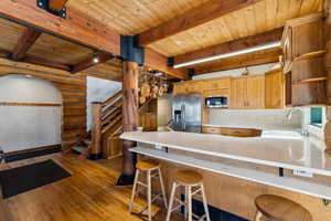 Kitchen with stainless steel appliances, a breakfast bar, light countertops, and a peninsula