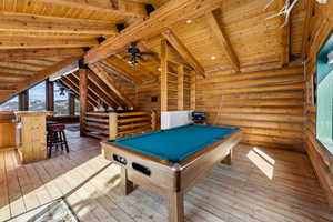 Playroom with lofted ceiling with beams, wooden ceiling, billiards, light wood-type flooring, and rustic walls