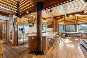 Kitchen featuring wooden ceiling, stainless steel appliances, dark wood-style floors, light brown cabinetry, and beamed ceiling