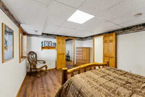 Bedroom with a paneled ceiling, visible vents, dark wood finished floors, and baseboards