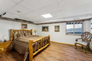 Bedroom featuring light wood-type flooring, visible vents, baseboards, and a paneled ceiling