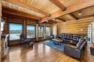 Living area featuring wood ceiling, log walls, wood finished floors, and beamed ceiling