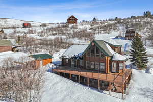 Snow covered back of property featuring a wooden deck