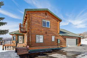 View of front facade with a garage, log exterior, roof with shingles, and driveway