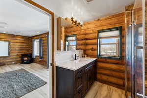 Bathroom with a wood stove, log walls, vanity, and wood finished floors