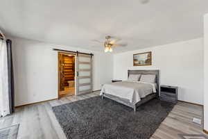 Bedroom featuring light wood-style floors, baseboards, and a barn door