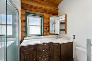 Bathroom featuring toilet, a stall shower, and vanity