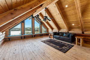 Interior space with log walls, wood-type flooring, lofted ceiling with beams, ceiling fan, and wooden ceiling