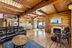 Living area with rustic walls, wood ceiling, beamed ceiling, rail lighting, and light wood-type flooring