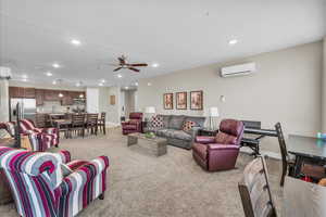 Living area with light carpet, a textured ceiling, an AC wall unit, and recessed lighting