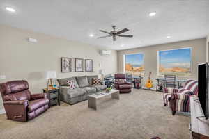 Living area with recessed lighting, light colored carpet, a textured ceiling, and a wall mounted AC