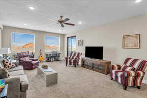 Living room featuring a textured ceiling, carpet floors, ceiling fan, and recessed lighting