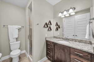 Bathroom with baseboards, toilet, tile patterned floors, vanity, and a shower stall