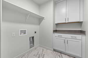 Clothes washing area with hookup for an electric dryer, washer hookup, baseboards, marble finish floor, and cabinet space