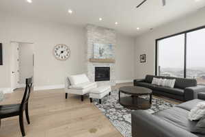 Living room with light wood-style floors, recessed lighting, baseboards, and a stone fireplace