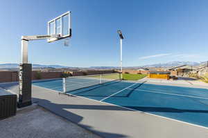 View of tennis court with fence and a mountain view