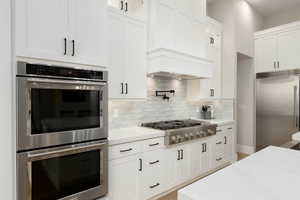 Kitchen featuring glass insert cabinets, white cabinetry, and stainless steel appliances