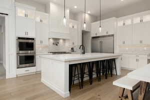 Kitchen with stainless steel appliances, light countertops, and white cabinets