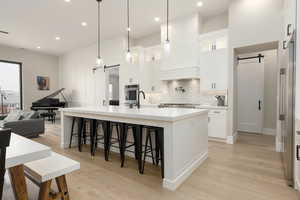 Kitchen with light countertops, a barn door, glass insert cabinets, white cabinetry, and stainless steel oven