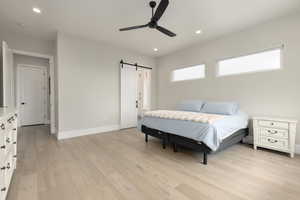 Bedroom featuring light wood finished floors, a barn door, baseboards, and recessed lighting