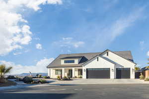 Modern inspired farmhouse featuring stone siding, driveway, an attached garage, and stucco siding