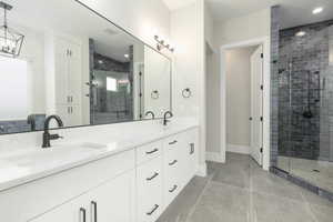 Bathroom with a stall shower, tile patterned flooring, a sink, and double vanity