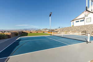 View of tennis court featuring community basketball court, a residential view, a mountain view, and fence