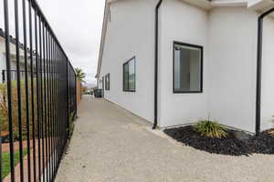 View of side of home featuring fence and stucco siding