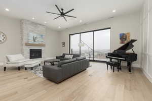 Living room with recessed lighting, a fireplace, visible vents, baseboards, and light wood finished floors