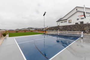 View of tennis court with a residential view, community basketball court, fence, and a yard