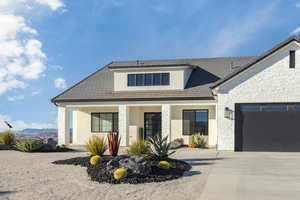 View of front of property featuring driveway, stone siding, an attached garage, and stucco siding