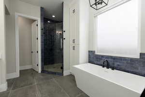 Bathroom featuring a wealth of natural light, tile patterned flooring, a freestanding bath, and a shower stall