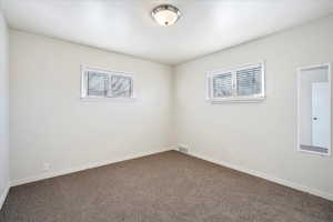 Empty room featuring carpet flooring, visible vents, and baseboards