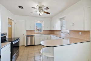 Kitchen with light countertops, appliances with stainless steel finishes, and white cabinets