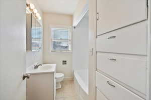 Full bath featuring a tub to relax in, tile patterned flooring, vanity, and toilet