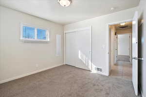 Unfurnished bedroom featuring light carpet, a closet, visible vents, and baseboards