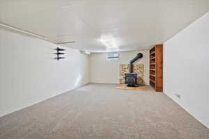 Basement featuring carpet, a wood stove, and visible vents