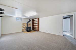 Below grade area with a wood stove, light carpet, and visible vents