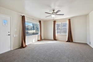 Carpeted spare room featuring ceiling fan, visible vents, and baseboards