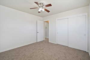 Unfurnished bedroom featuring carpet, arched walkways, a closet, ceiling fan, and baseboards