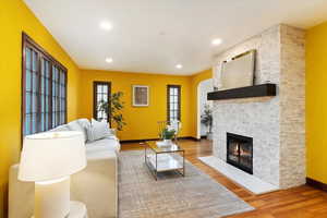 Living room with recessed lighting, a fireplace, baseboards, and wood finished floors