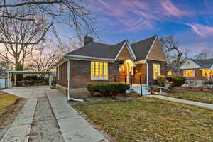 View of front of home featuring driveway, a chimney, a front lawn, and brick siding