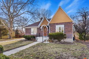 View of front facade featuring a front yard, brick siding, and a chimney