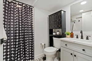 Bathroom featuring toilet, a shower with shower curtain, vanity, and recessed lighting