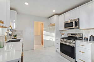 Kitchen featuring marble finish floor, recessed lighting, appliances with stainless steel finishes, white cabinetry, and a sink