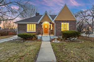 View of front of house featuring a chimney, a front lawn, and brick siding