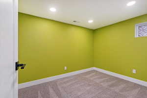 Carpeted empty room featuring baseboards, visible vents, and recessed lighting